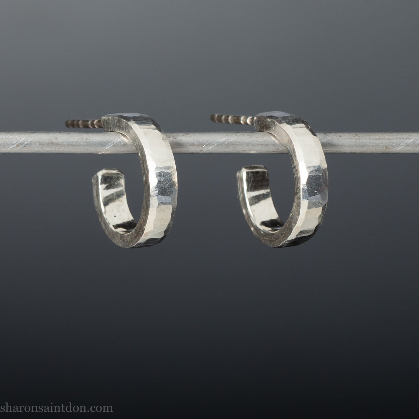 A close-up view of handcrafted solid silver hoop earrings, 14mm diameter x 3mm wide x 1.5mm thick with a hammered matte finish.