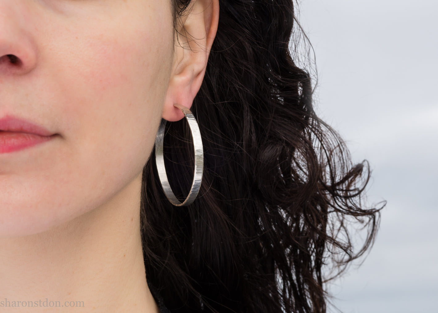 Handmade sterling silver hoop earrings. 50mm diameter, 5mm wide, with a hammered surface and brushed, matte, shiny finish.
