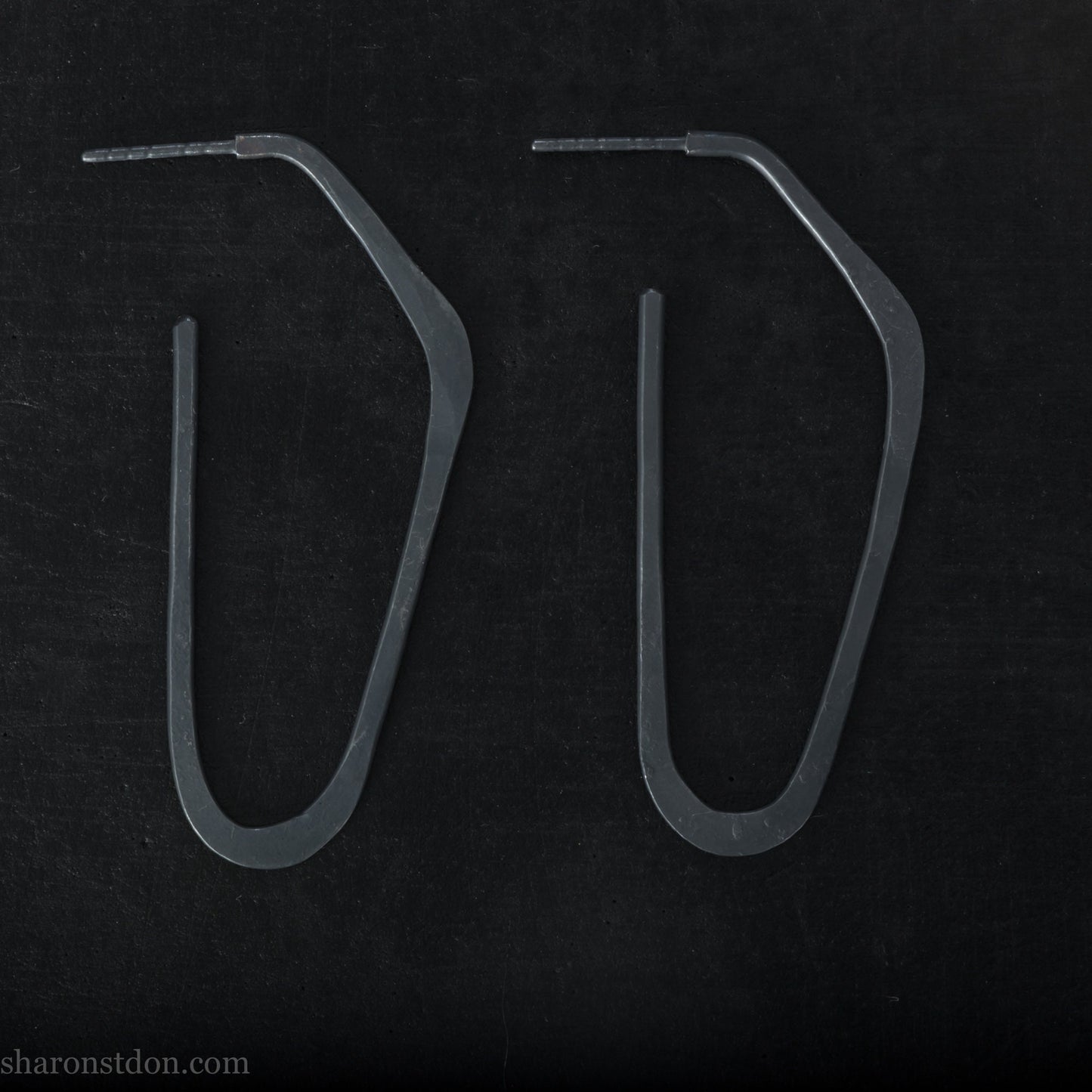 925 sterling silver hoop earrings handmade in North America by Sharon SaintDon. Long, angular, high D shape, oxidized black with hammered texture. SIZE: 47mm high x 19mm wide