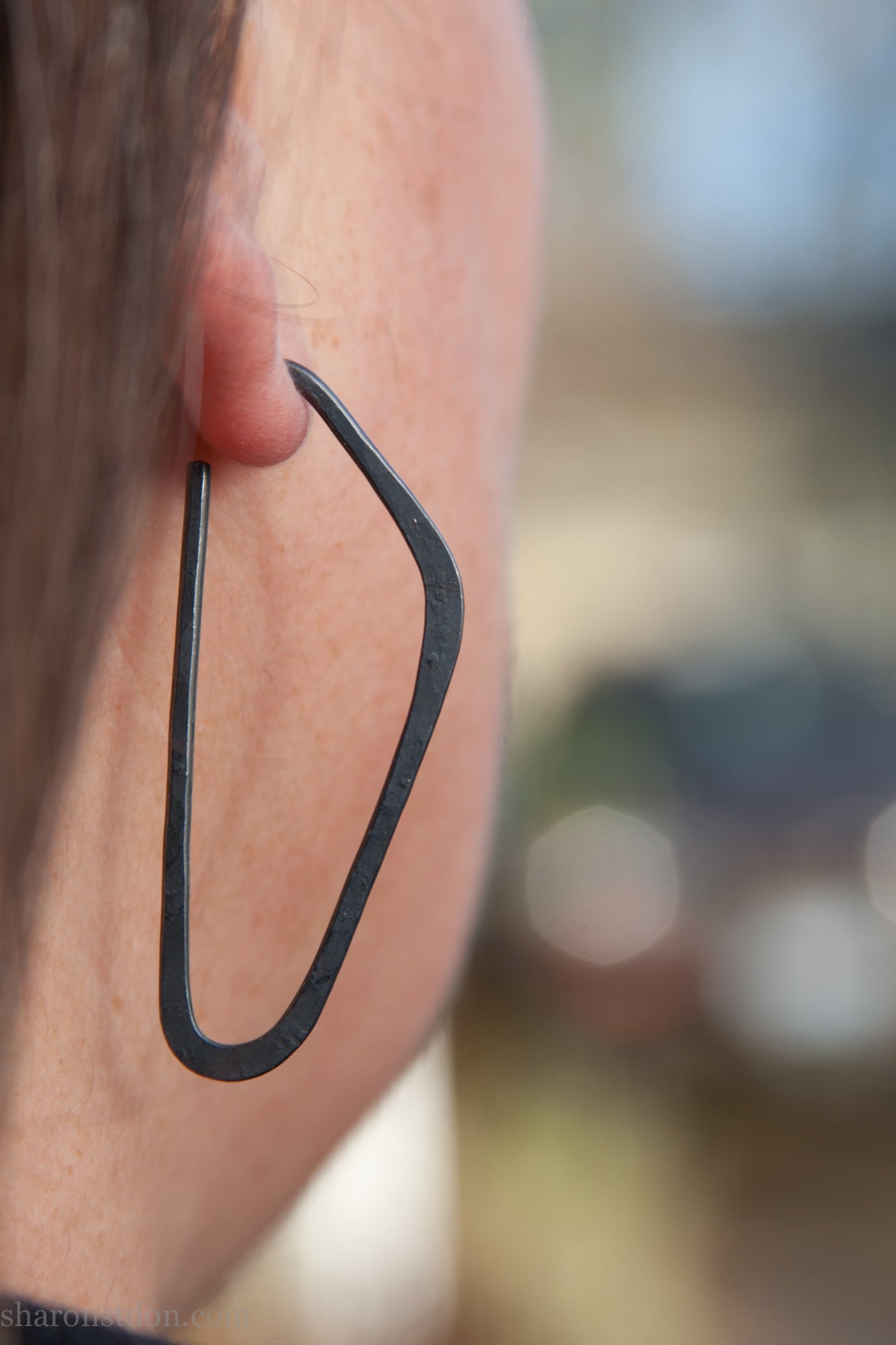 oxidized black sterling silver high D hoop earrings with hammered texture, 47mm long, shown on model’s ear.
