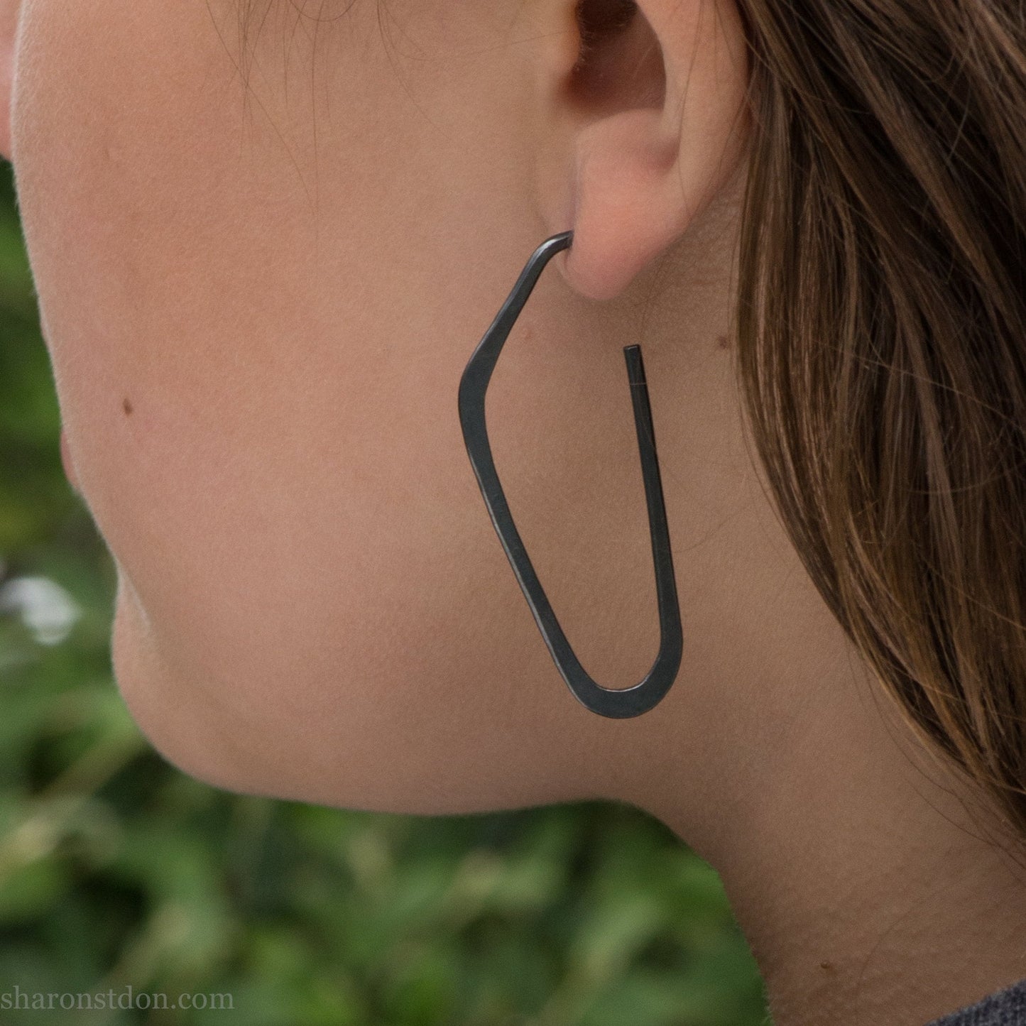 oxidized black sterling silver high D hoop earrings with hammered texture, 47mm long, shown on model’s ear