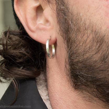 Hand hammered solid 925 sterling silver hoop earrings with a matte, brushed, finish. 20mm diameter x 2mm wide x 1.5mm thick, worn on an ear.