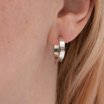 Close-up of a woman’s ear wearing a handcrafted 16mm sterling silver hoop earring with a matte hammered finish.