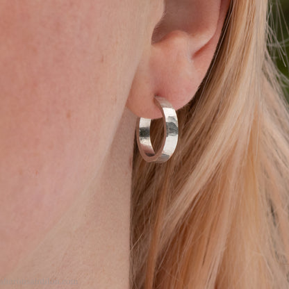 Close-up of a woman’s ear wearing a handcrafted 16mm sterling silver hoop earring with a matte hammered finish.