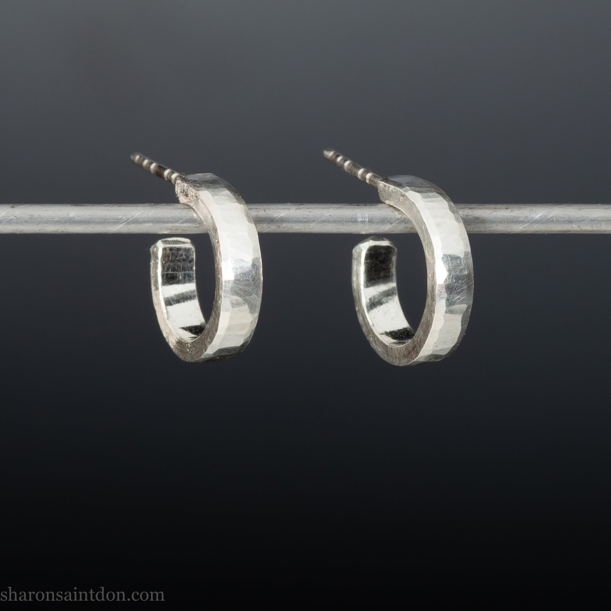 Close-up of handcrafted 16mm sterling silver hoop earrings with a matte hammered finish.