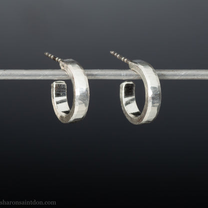 Close-up of handcrafted 16mm sterling silver hoop earrings with a matte hammered finish.
