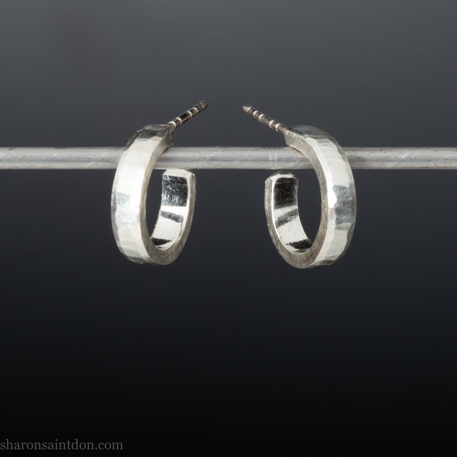 Close-up of handcrafted 16mm sterling silver hoop earrings with a matte hammered finish.