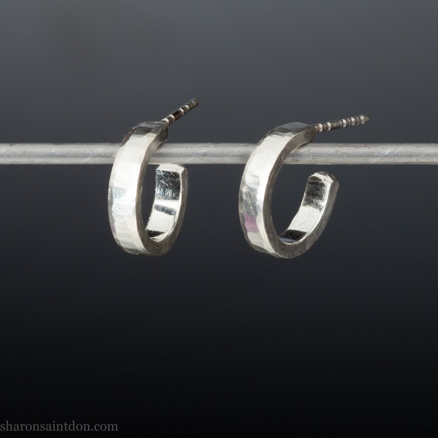 Close-up of handcrafted 16mm sterling silver hoop earrings with a matte hammered finish.