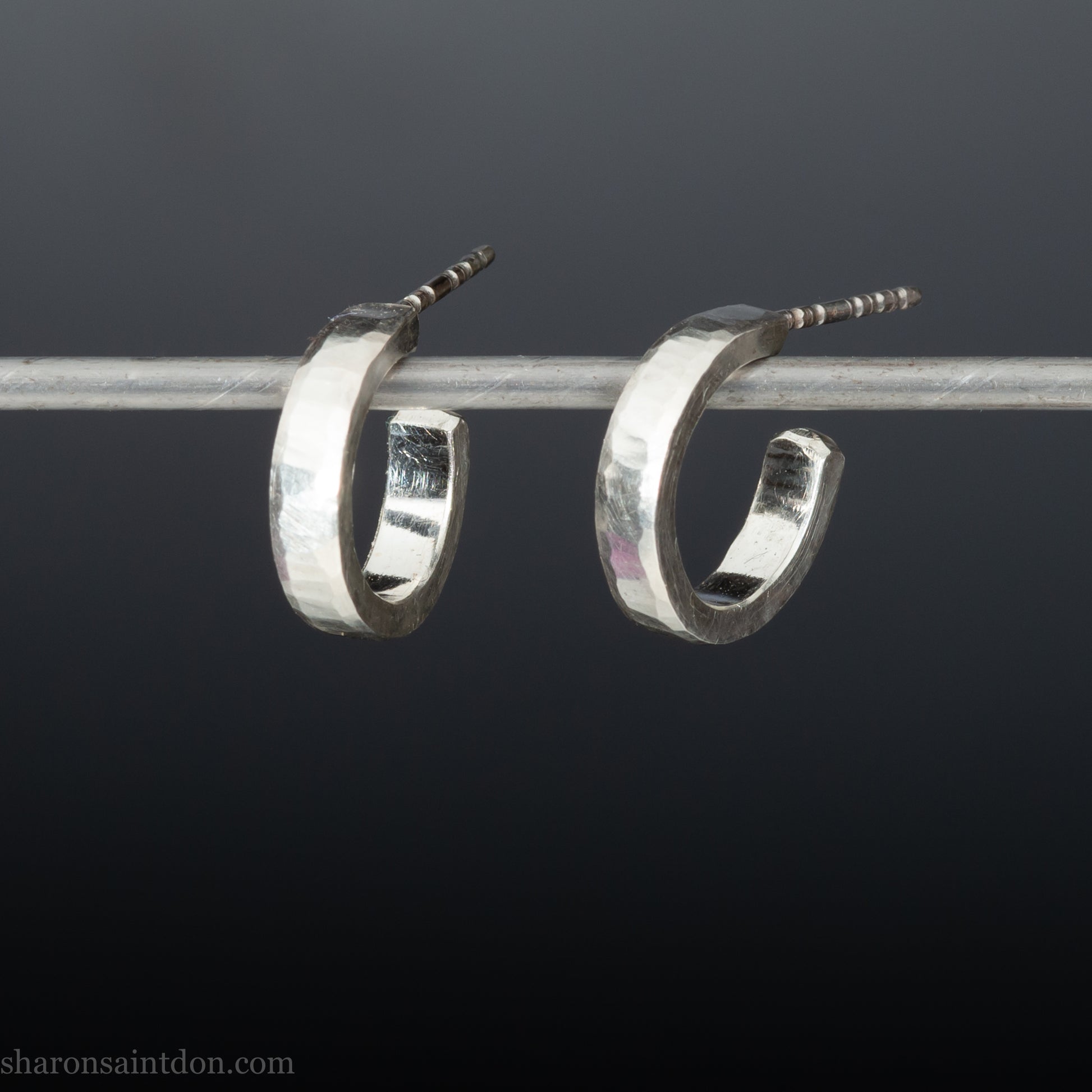 Close-up of handcrafted 16mm sterling silver hoop earrings with a matte hammered finish.