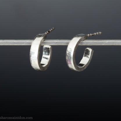 Close-up of handcrafted 16mm sterling silver hoop earrings with a matte hammered finish.