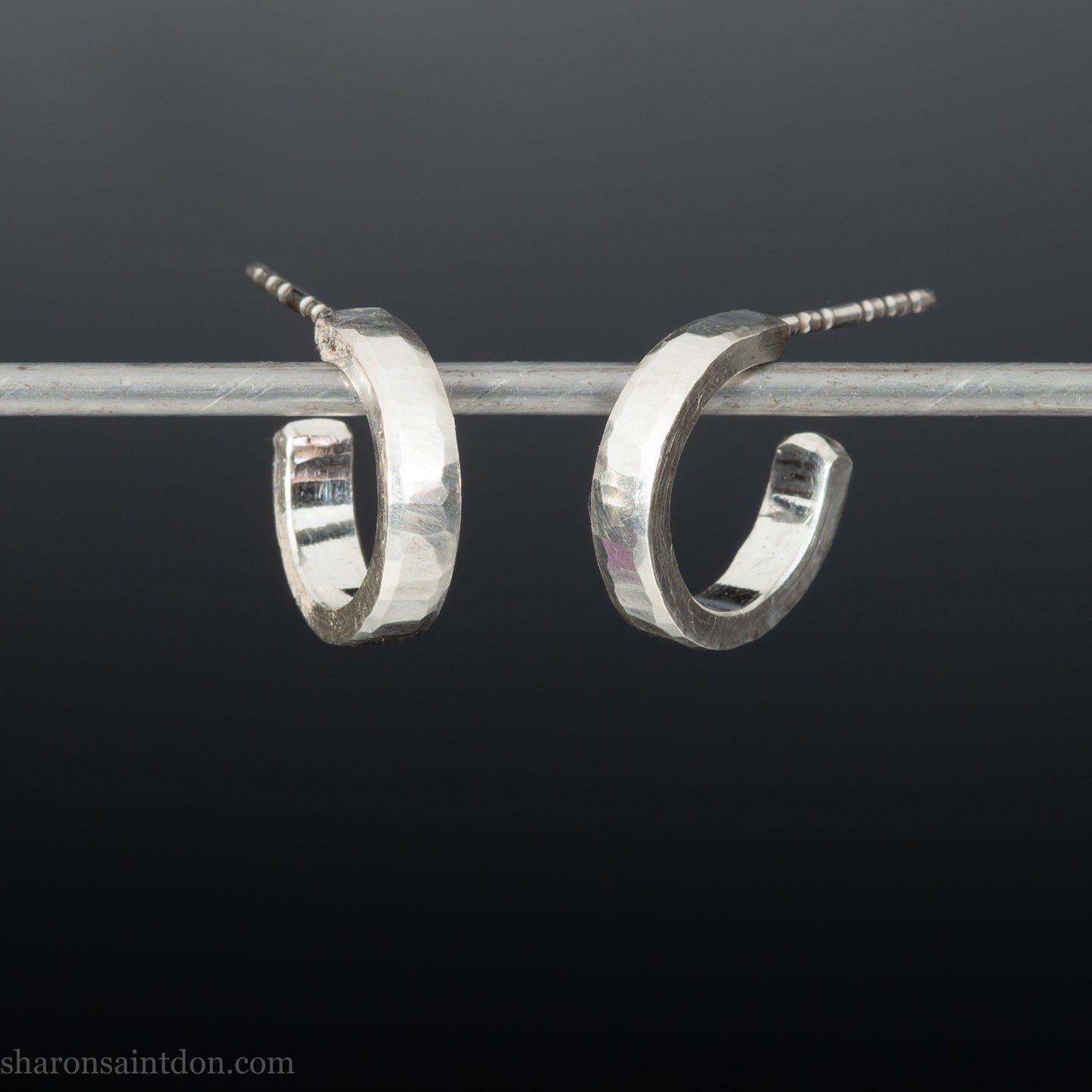 Close-up of handcrafted 16mm sterling silver hoop earrings with a matte hammered finish.