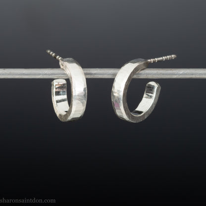 Close-up of handcrafted 16mm sterling silver hoop earrings with a matte hammered finish.