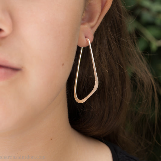 Woman wearing solid 925 sterling silver hoop earrings, angular low D shape, hand hammered.