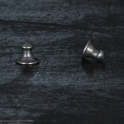 Pair of earrings backs on a dark textured background