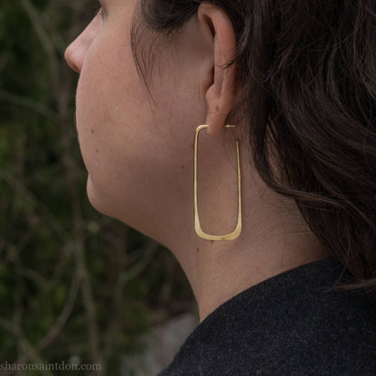 Large gold hoop earrings handmade by Sharon SaintDon in the Pacific Northwest of North America.  Hand forged solid 18k yellow gold rectangles, 2cm wide x 5cm long with a matte brushed finish. The locking backs and posts are also solid 18k gold.