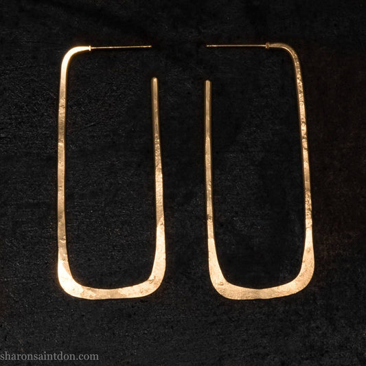 Large gold hoop earrings handmade by Sharon SaintDon in the Pacific Northwest of North America.  Hand forged solid 18k yellow gold rectangles, 2cm wide x 5cm long with a matte brushed finish. The locking backs and posts are also solid 18k gold.