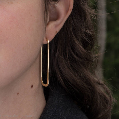 Large gold hoop earrings handmade by Sharon SaintDon in the Pacific Northwest of North America.  Hand forged solid 18k yellow gold rectangles, 2cm wide x 5cm long with a matte brushed finish. The locking backs and posts are also solid 18k gold.