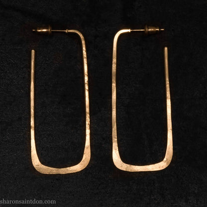 Large gold hoop earrings handmade by Sharon SaintDon in the Pacific Northwest of North America.  Hand forged solid 18k yellow gold rectangles, 2cm wide x 5cm long with a matte brushed finish. The locking backs and posts are also solid 18k gold.