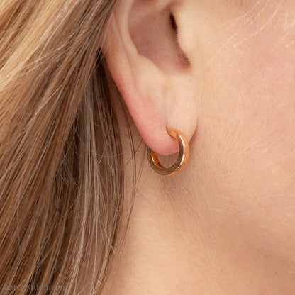 Solid 18k yellow gold hoop earrings set, handmade in North America by Sharon SaintDon. 12mm diameter round, 2mm wide, 1.5mm thick, with hammered texture and matte finish.