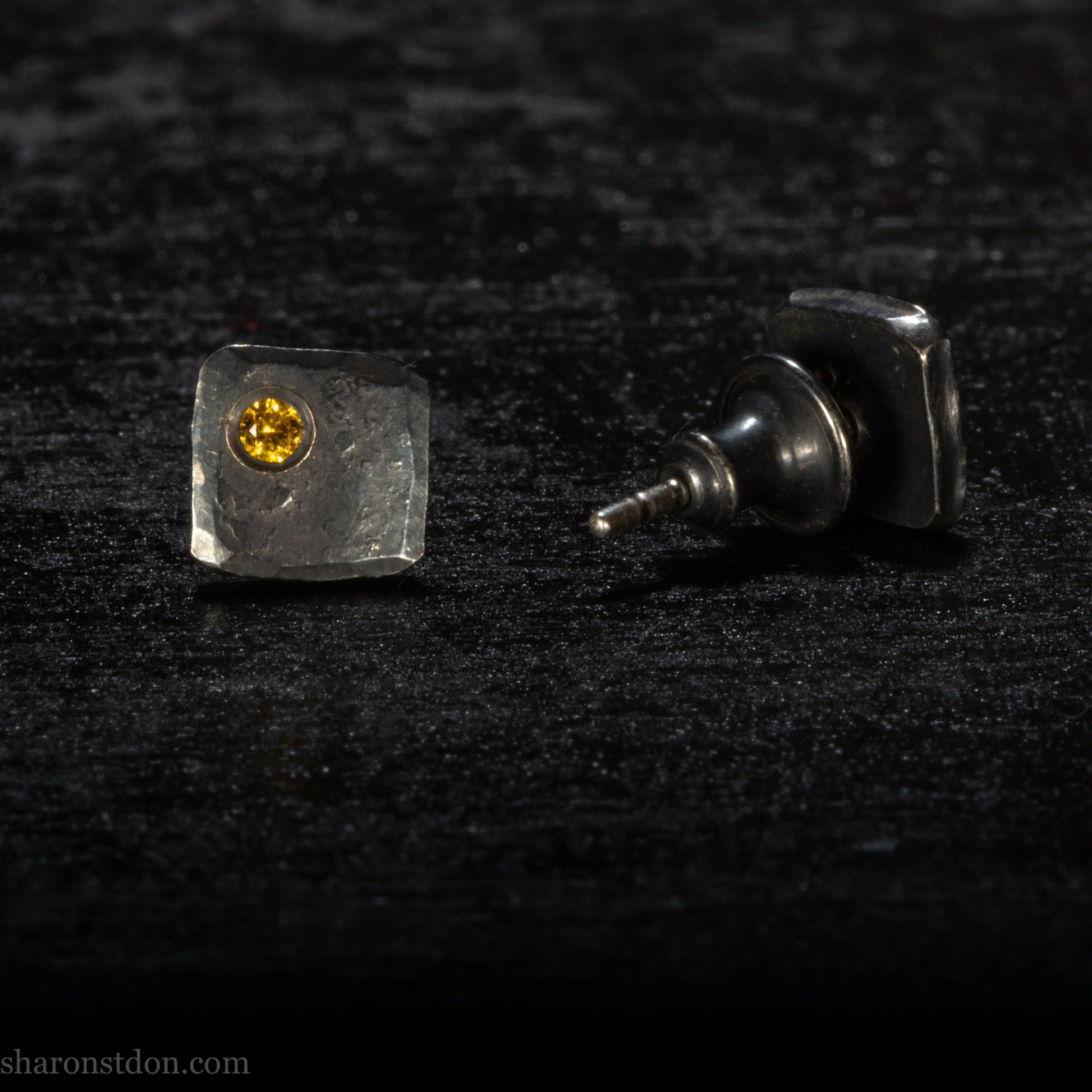Handmade 925 sterling silver stud earrings handmade by Sharon SaintDon In North America. 7mm x 7mm hammered, square, oxidized black silver with a 2mm round lab grown golden yellow topaz gemstone in the corner.