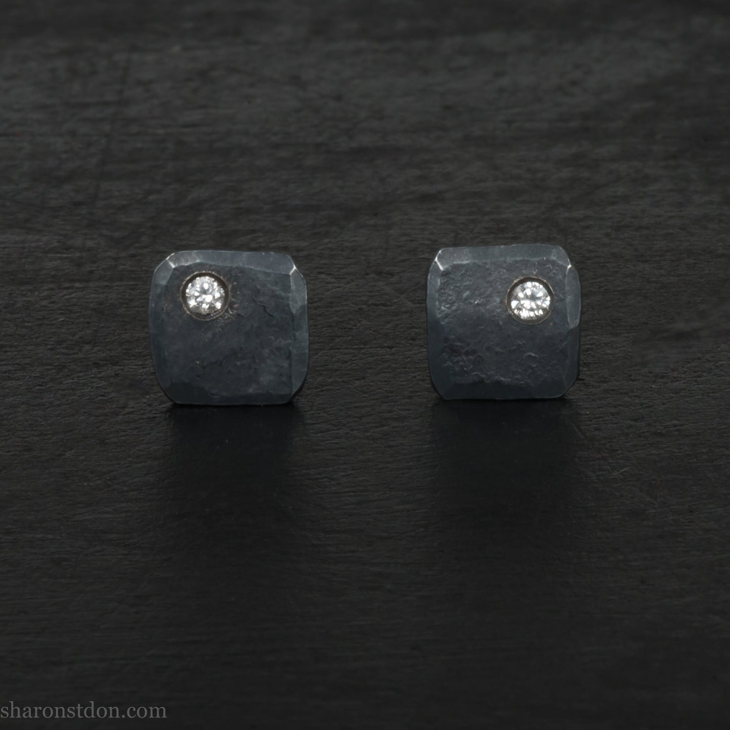 Solid 925 sterling silver stud earrings with 2mm round cubic zirconia lab grown gemstone set in the corner. 7mm square, 1.5mm thick, hammered silver with black oxidized tarnished finish. Handmade by Sharon SaintDon in the USA.