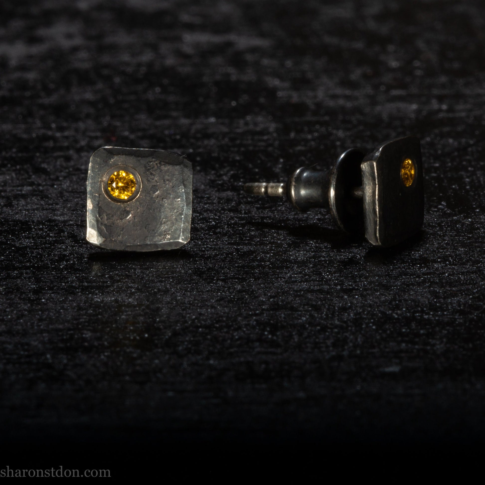 Handmade 925 sterling silver stud earrings handmade by Sharon SaintDon In North America. 7mm x 7mm hammered, square, oxidized black silver with a 2mm round lab grown golden yellow topaz gemstone in the corner.