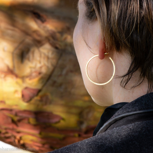40mm diameter by 1.5mm thick handmade solid 14k yellow gold hoop earrings. Handmade by Sharon SaintDon in North America. Hammered from solid gold with a matte finish.