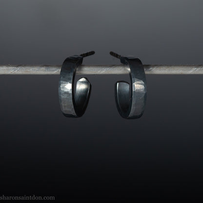 Handmade 925 sterling silver hoop earrings for men or women. 16mm x 3mm, round, oxidized black earrings with hammered texture, made by Sharon SaintDon in North America.