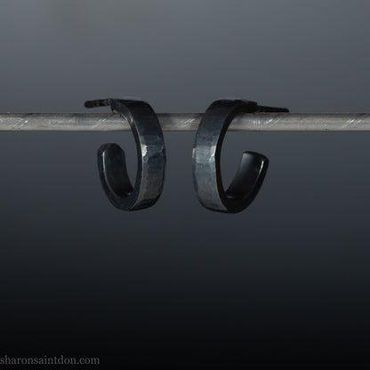 Handmade 925 sterling silver hoop earrings for men or women. 16mm x 3mm, round, oxidized black earrings with hammered texture, made by Sharon SaintDon in North America.