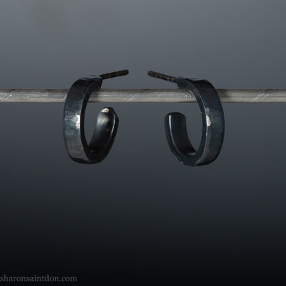 Handmade 925 sterling silver hoop earrings for men or women. 16mm x 3mm, round, oxidized black earrings with hammered texture, made by Sharon SaintDon in North America.
