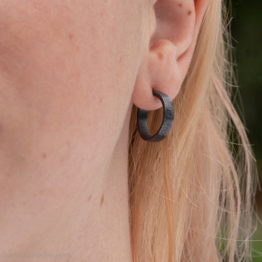 Handmade 925 sterling silver hoop earrings for men or women. 16mm x 3mm, round, oxidized black earrings with hammered texture, made by Sharon SaintDon in North America.
