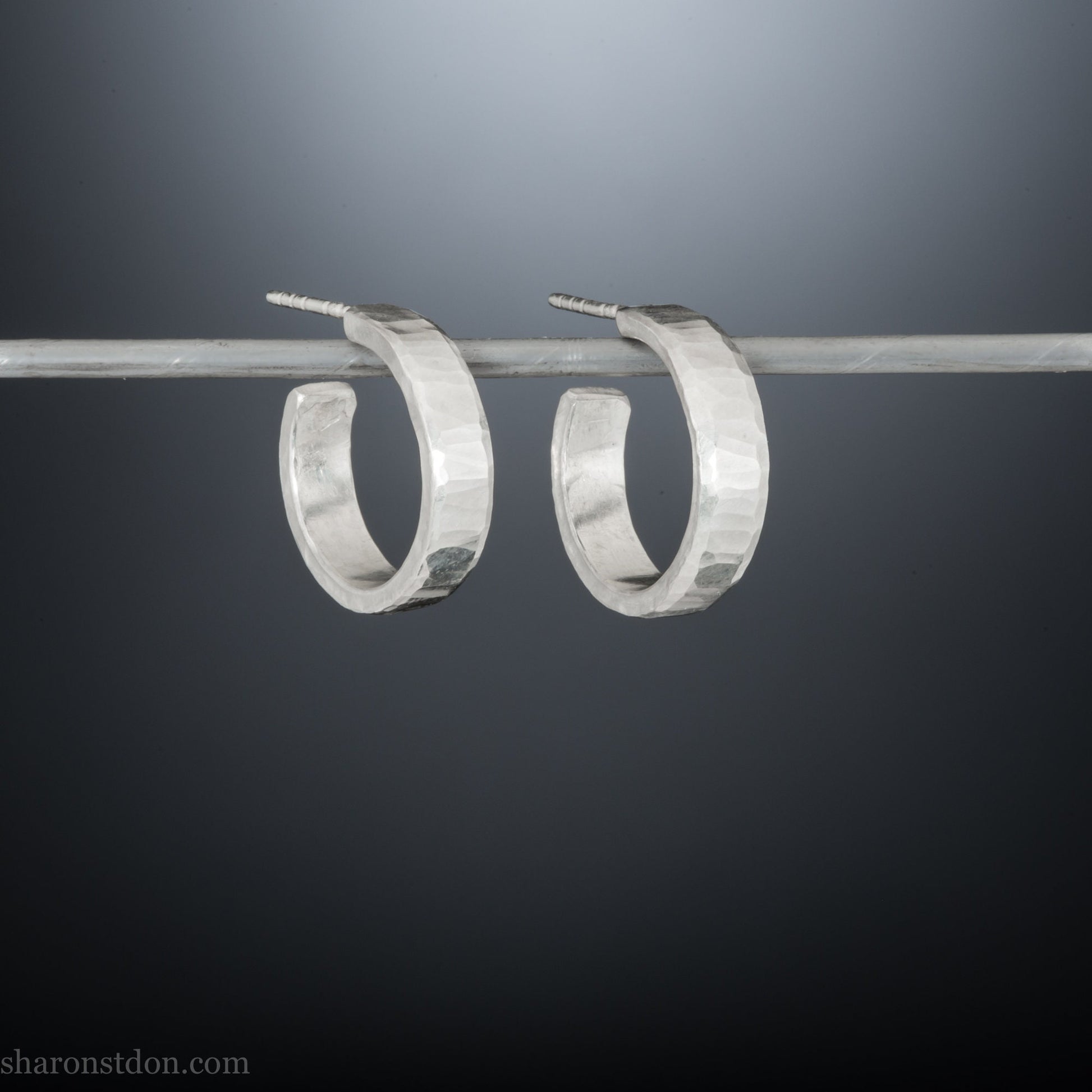 Small sterling silver hoop earrings, Handmade in North America by Sharon SaintDon. 18 x 4 x 1.5mm thick. Solid hammered silver with a matte, brushed finish, silver posts and backs.