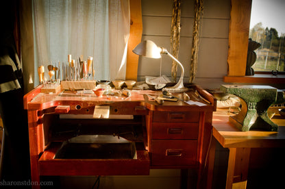Wooden desk with lamp and various items in a cozy room.