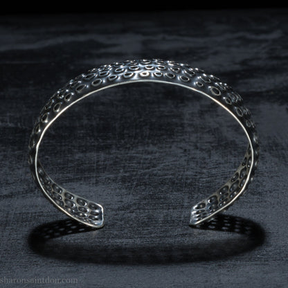 925 sterling silver cuff bracelet handmade in USA. 2cm wide, 40cm x 60cm oval with approximately 28mm flexible opening for wrist. Punched perforated hole texture, oxidized black and rubbed back to show circles as white shiny silver.