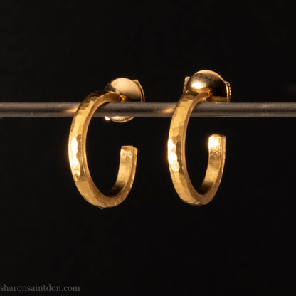 Solid yellow gold hoop earrings handmade in North America by Sharon SaintDon. Hammered solid 18k yellow gold, 18mm diameter round. Matte brushed finish and solid 18k gold posts and locking backs.