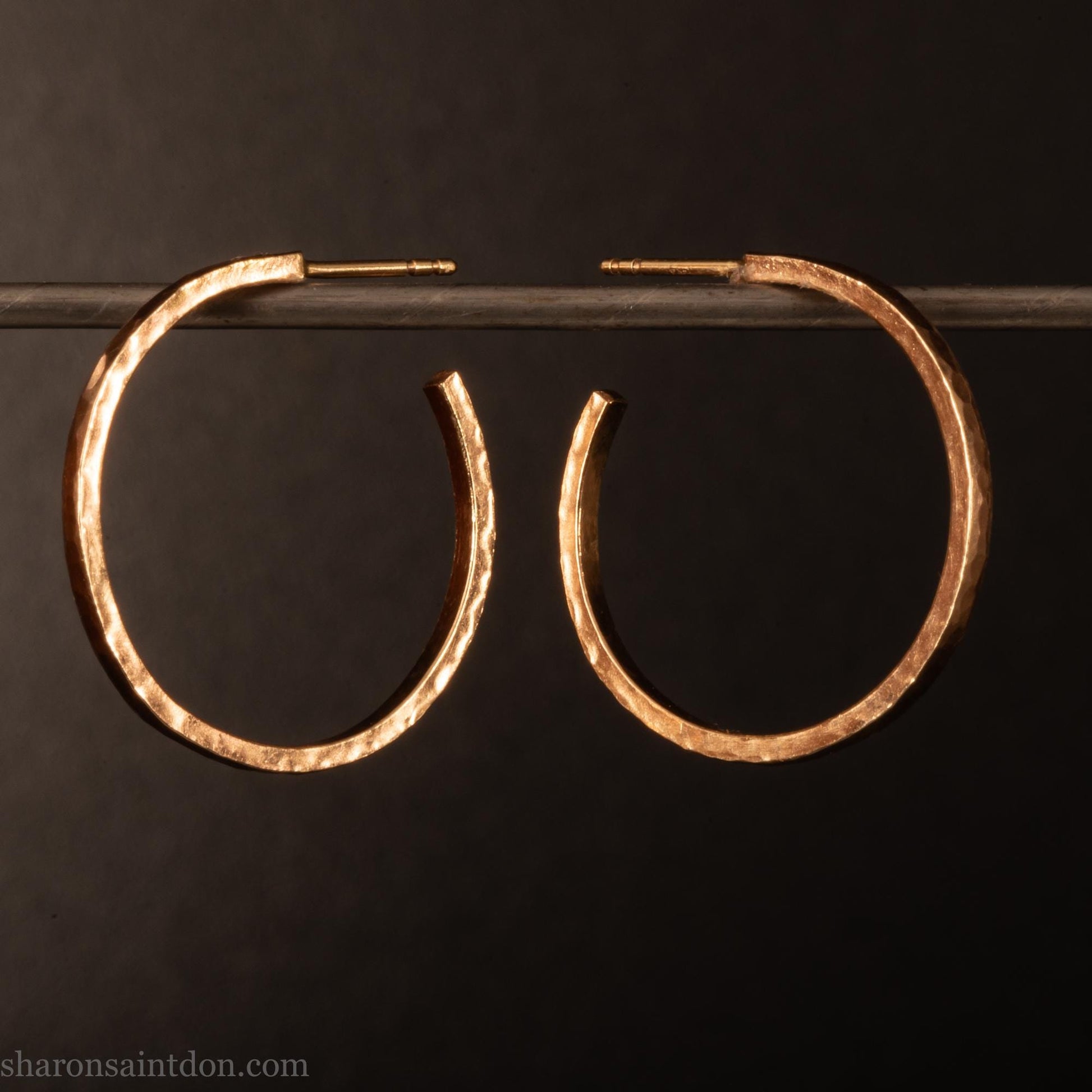 25mm diameter by 1.5mm thick  solid 14k yellow gold hoop earrings. Solid 14k gold posts and backs. Handmade by Sharon SaintDon in North America. Hammered from solid gold with a matte finish.
