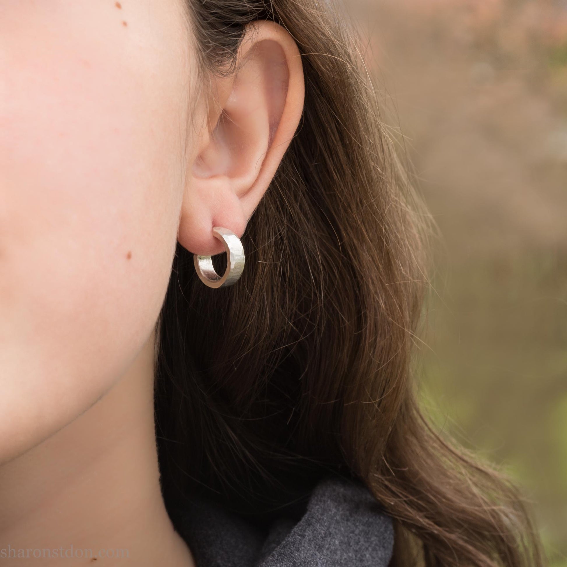 Solid sterling silver hoop earrings handmade in North America by Sharon SaintDon. Solid hammered silver with a matte brushed finish. 14mm diameter, 4mm wide, 1.5mm thick, solid silver posts and backs.