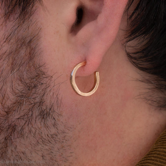 Solid yellow gold hoop earrings handmade in North America by Sharon SaintDon. Hammered solid 18k yellow gold, 18mm diameter round. Matte brushed finish and solid 18k gold posts and locking backs.