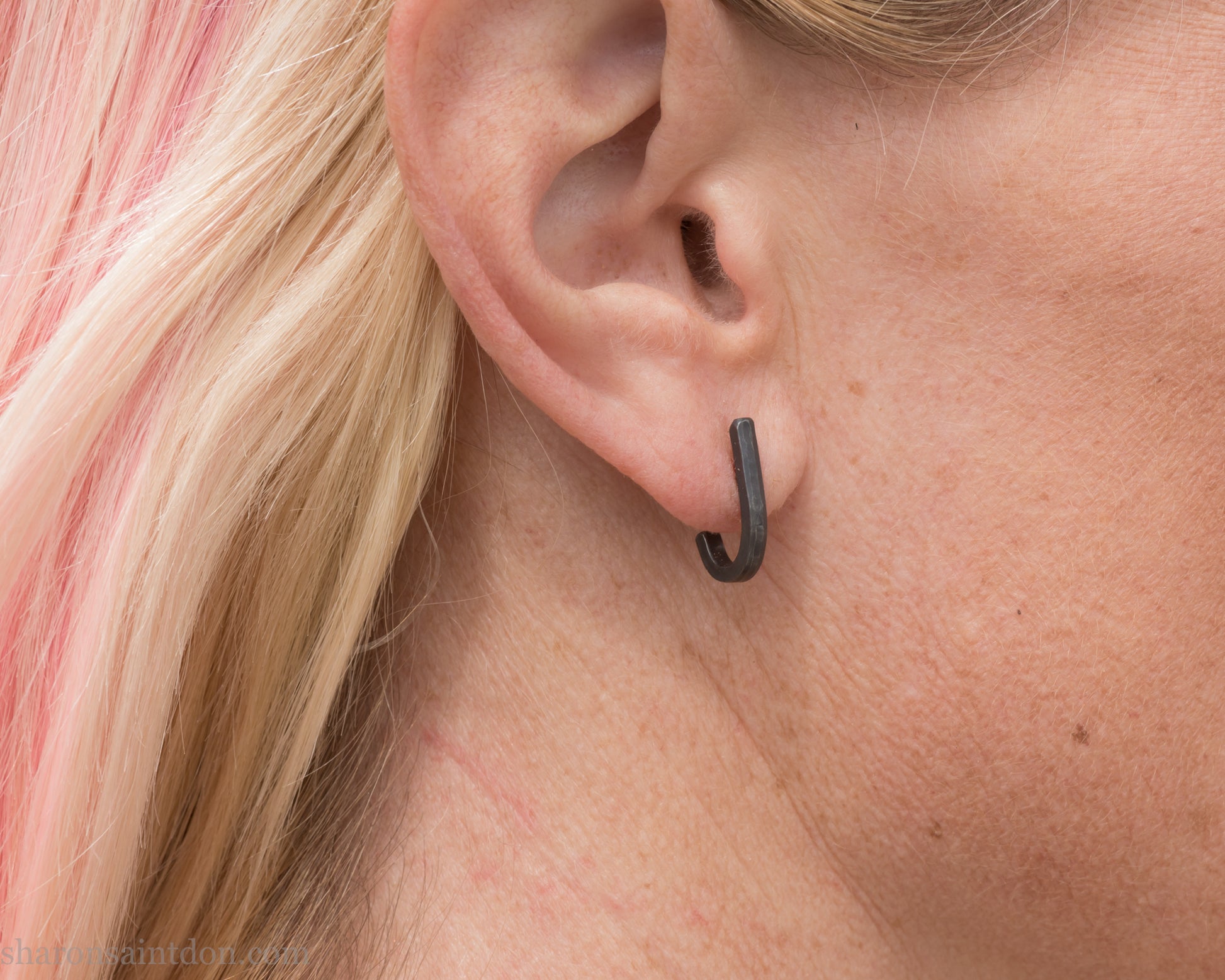 Hand hammered oxidized black sterling silver J-Curve hoop earrings, oxidized black patina, worn on ear.