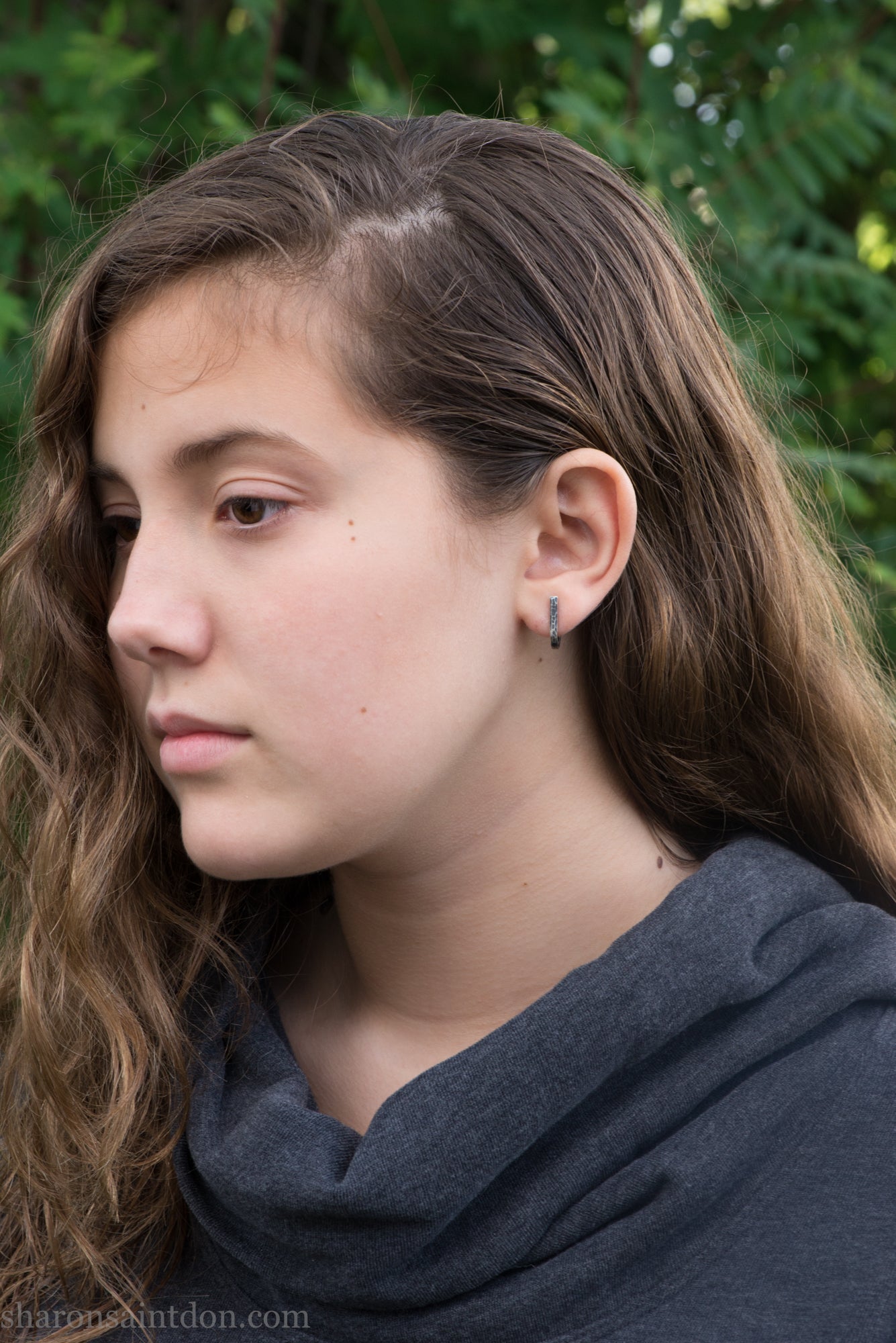 Hand hammered oxidized sterling silver J-wrap hoop earring, dark antique patina, worn on ear.