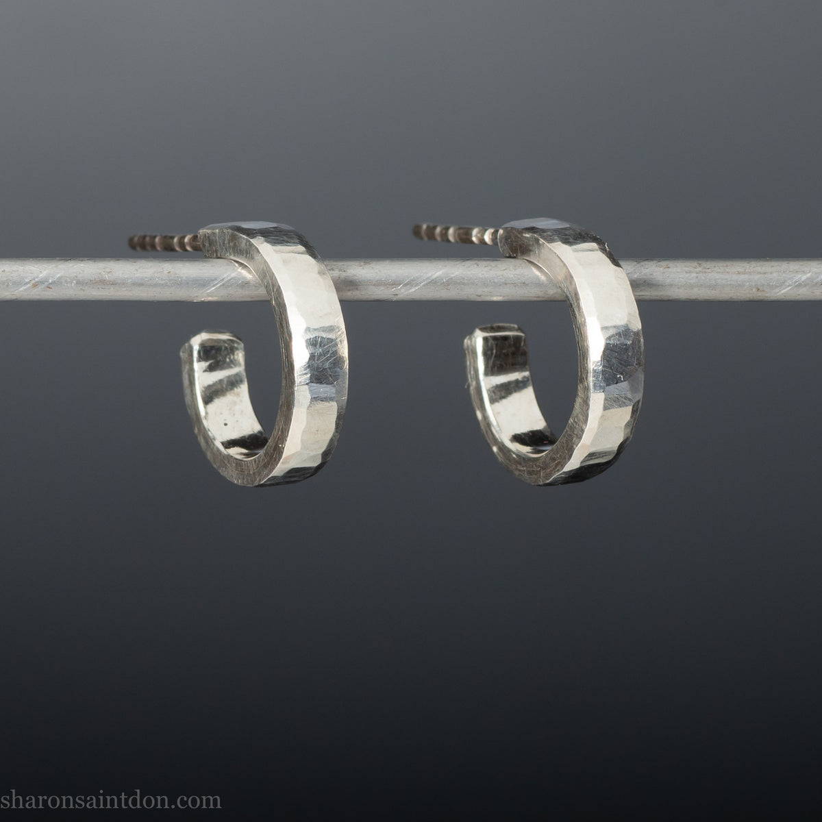 A close-up view of handcrafted solid silver hoop earrings, 14mm diameter x 3mm wide x 1.5mm thick with a hammered matte finish.