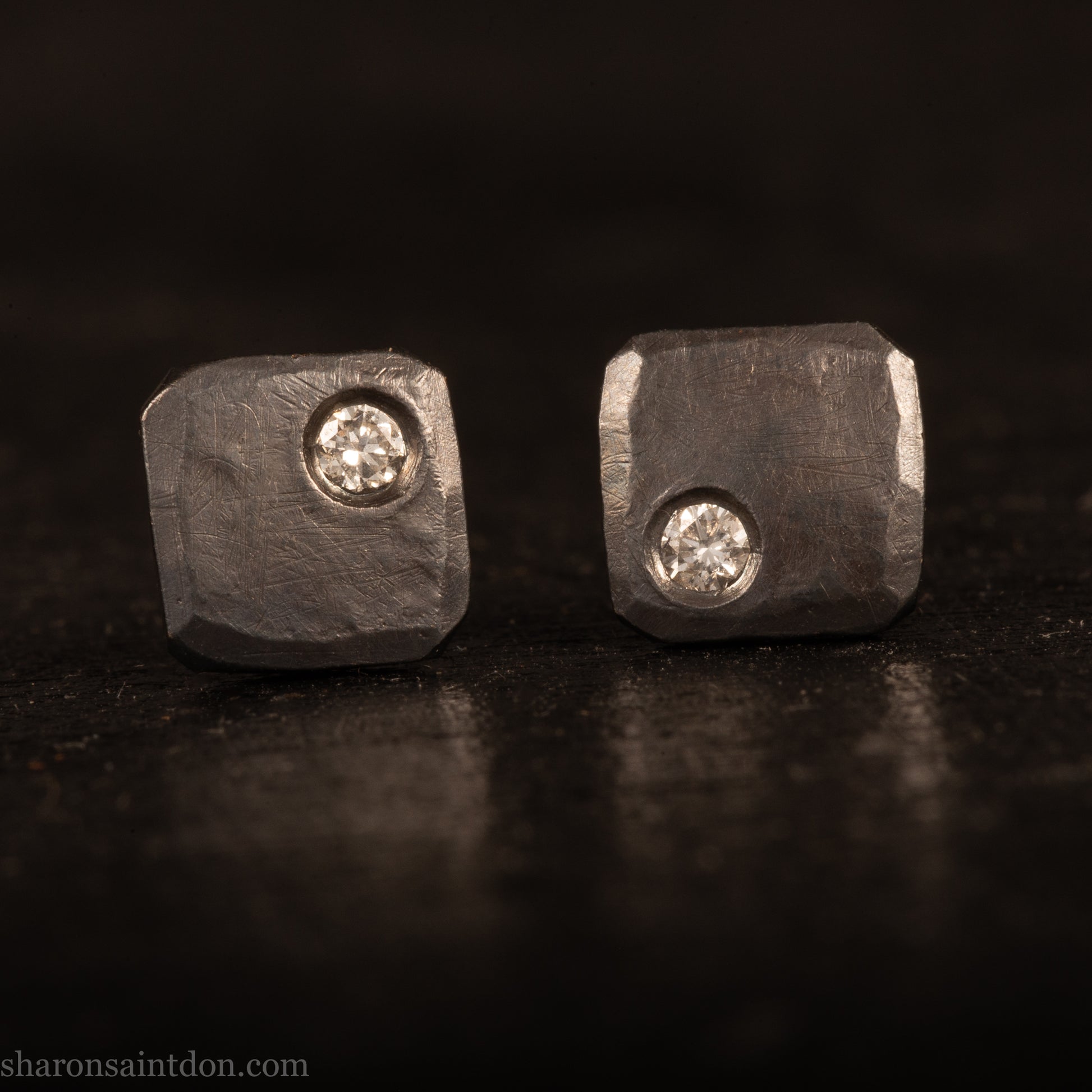 Handcrafted 925 sterling silver stud earrings with moissanite, lab grown, alternative diamond gemstones. 7mm square, 1.5mm thick, solid hammered silver with oxidized black finish. 2mm round moissanite is set in the corner, posts and backs are sterling silver.