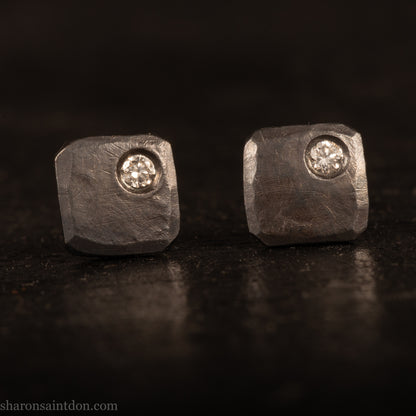 Handcrafted 7mm square sterling silver stud earrings, oxidized black with a 2mm round moissanite gemstone set in the corner.