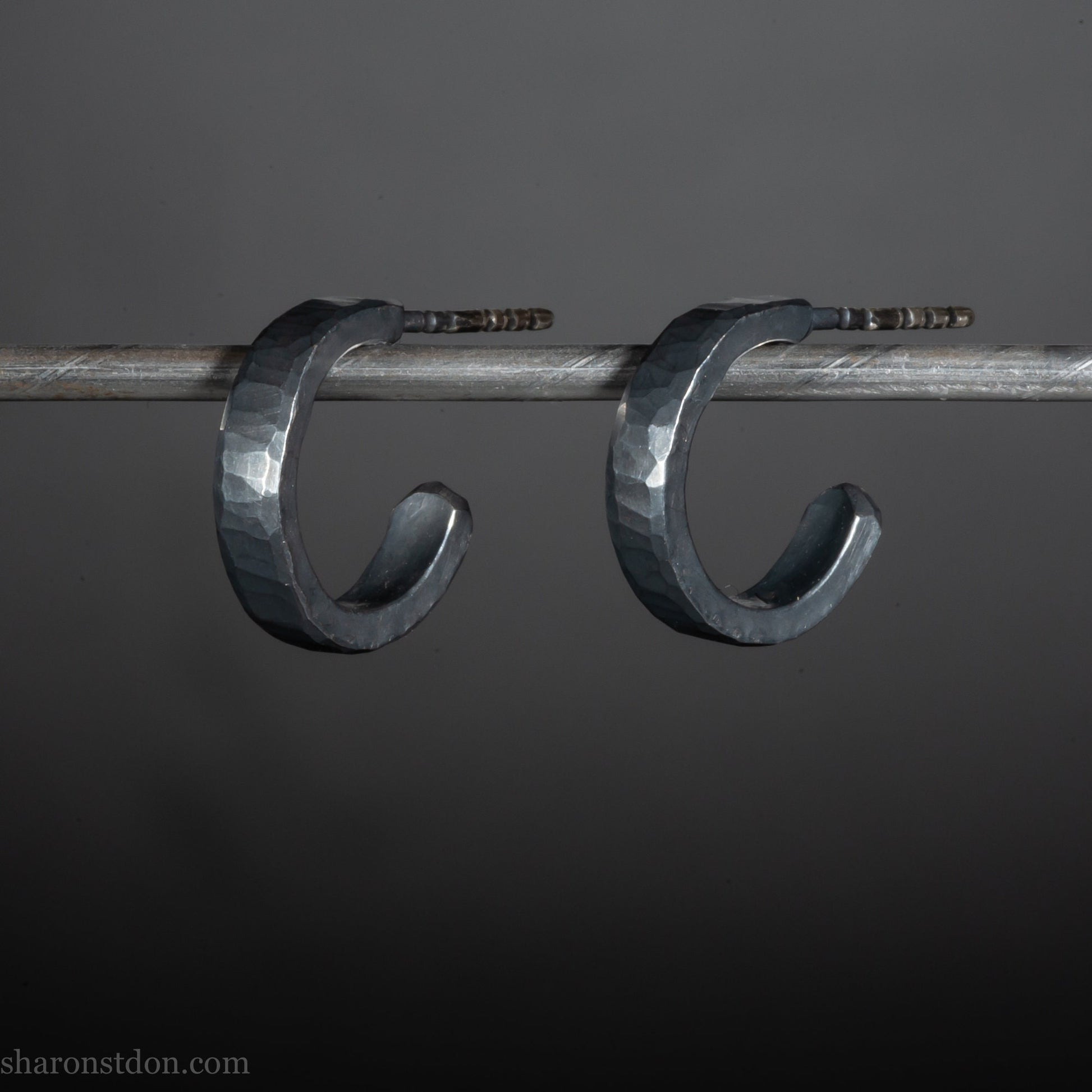 Close up photo of oxidized black, handcrafted 14mm x 3mm hammered solid sterling silver hoop earrings.