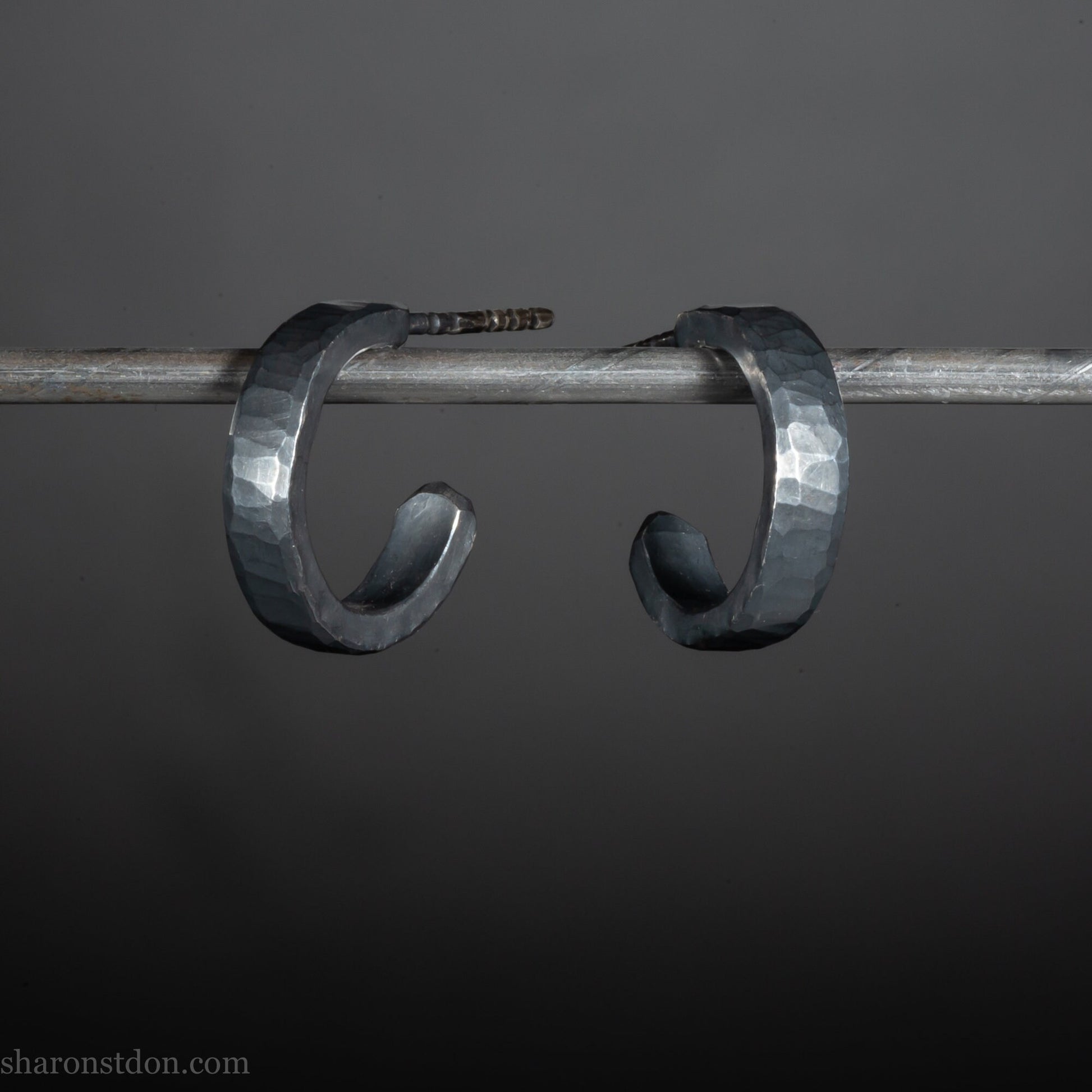 Close up photo of oxidized black, handcrafted 14mm x 3mm hammered solid sterling silver hoop earrings.