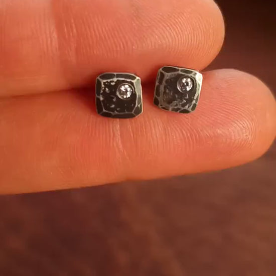 Small 925 sterling silver stud earrings for men with 2mm, imitation diamond gemstone set in the corner. 7mm square, 1.5mm thick with silver posts and backs and hammered, dark, antiqued finish. Handcrafted by Sharon Saint Don in North America.