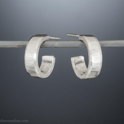 Close up photo of handcrafted 14mm x 4mm hammered solid sterling silver hoop earrings.
