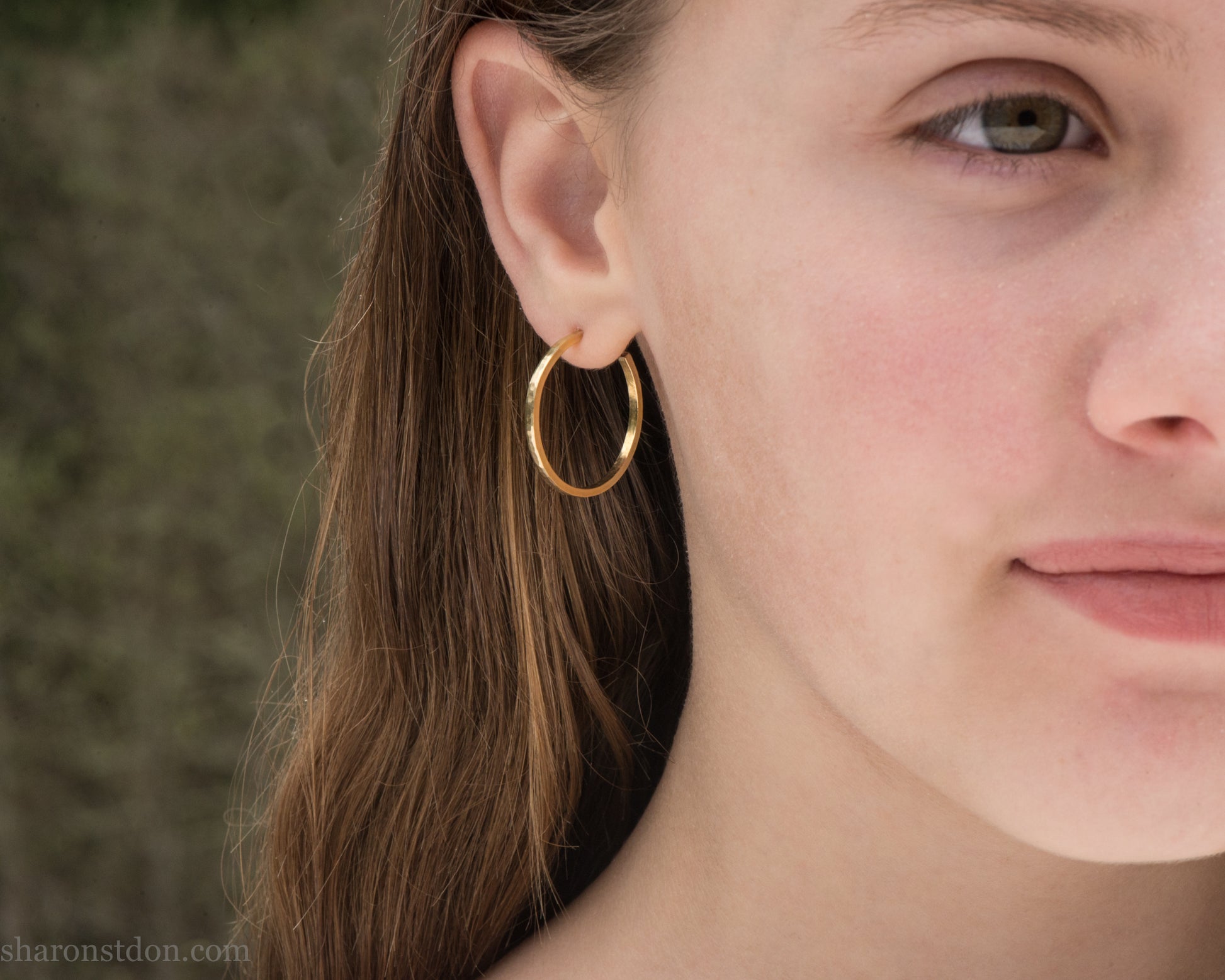 25mm solid yellow gold hoop earrings with hammered matte finish and solid gold posts, handmade by Sharon SaintDon.