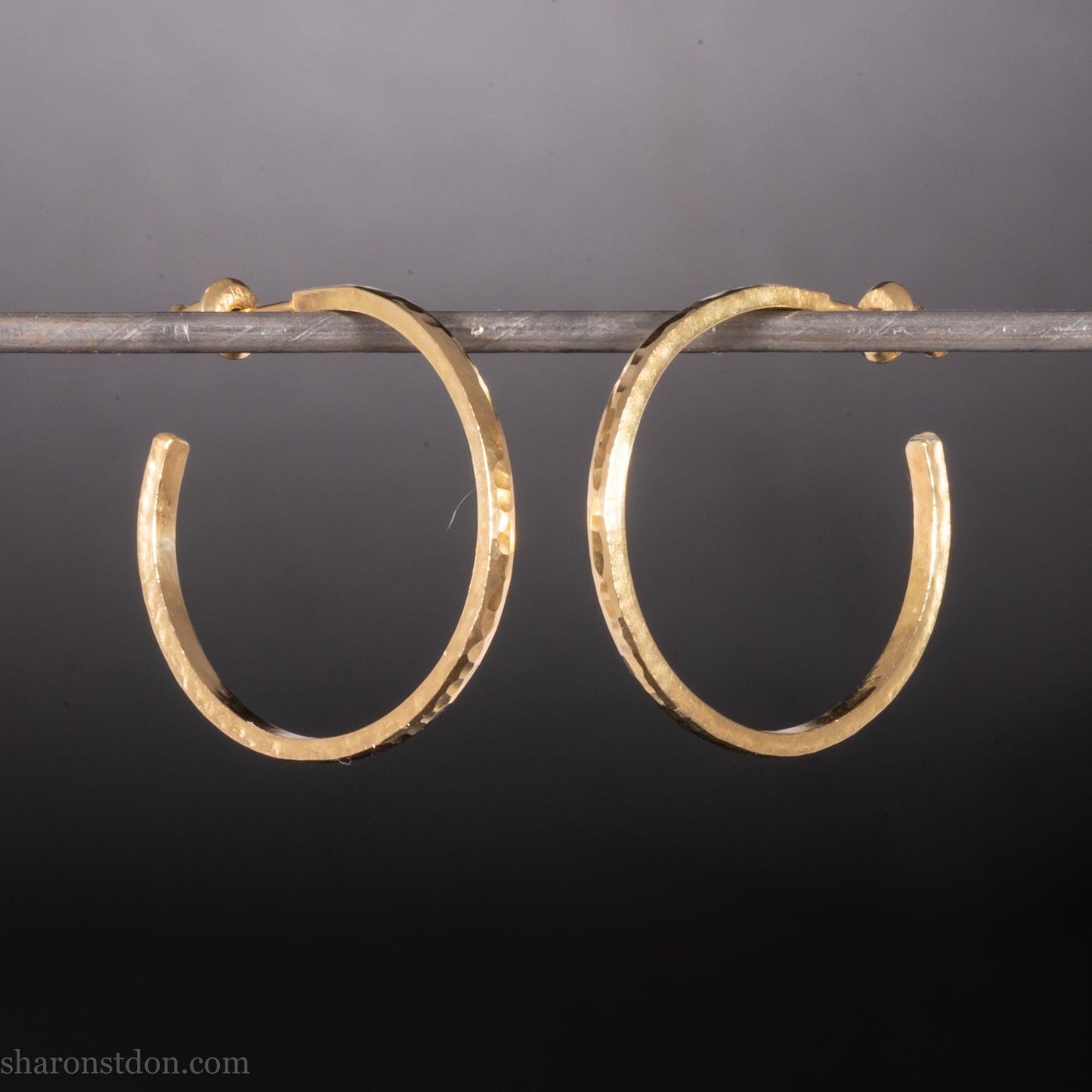 Solid 14k gold hoop earrings handmade in North America by Sharon SaintDon. Solid hammered yellow gold with a matte brushed finish. 25mm diameter round, 1.5mm thick, solid gold posts and backs.