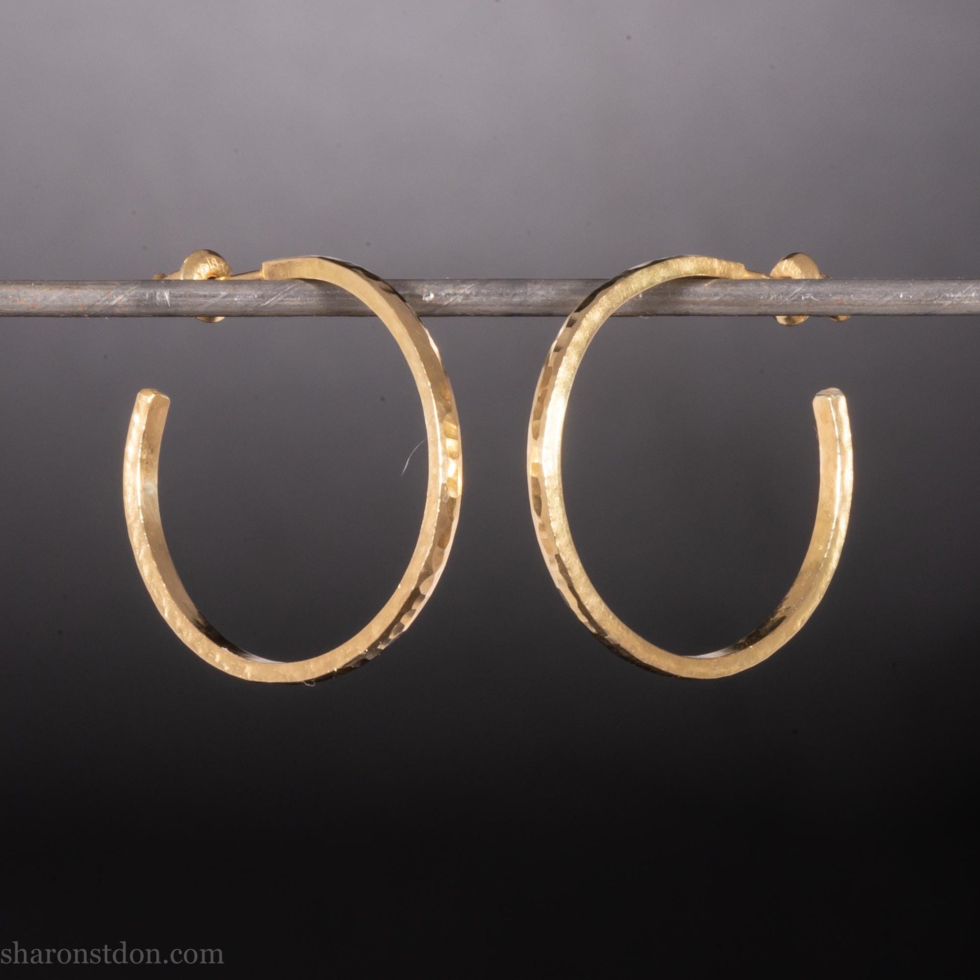Solid 14k gold hoop earrings handmade in North America by Sharon SaintDon. Solid hammered yellow gold with a matte brushed finish. 25mm diameter round, 1.5mm thick, solid gold posts and backs.